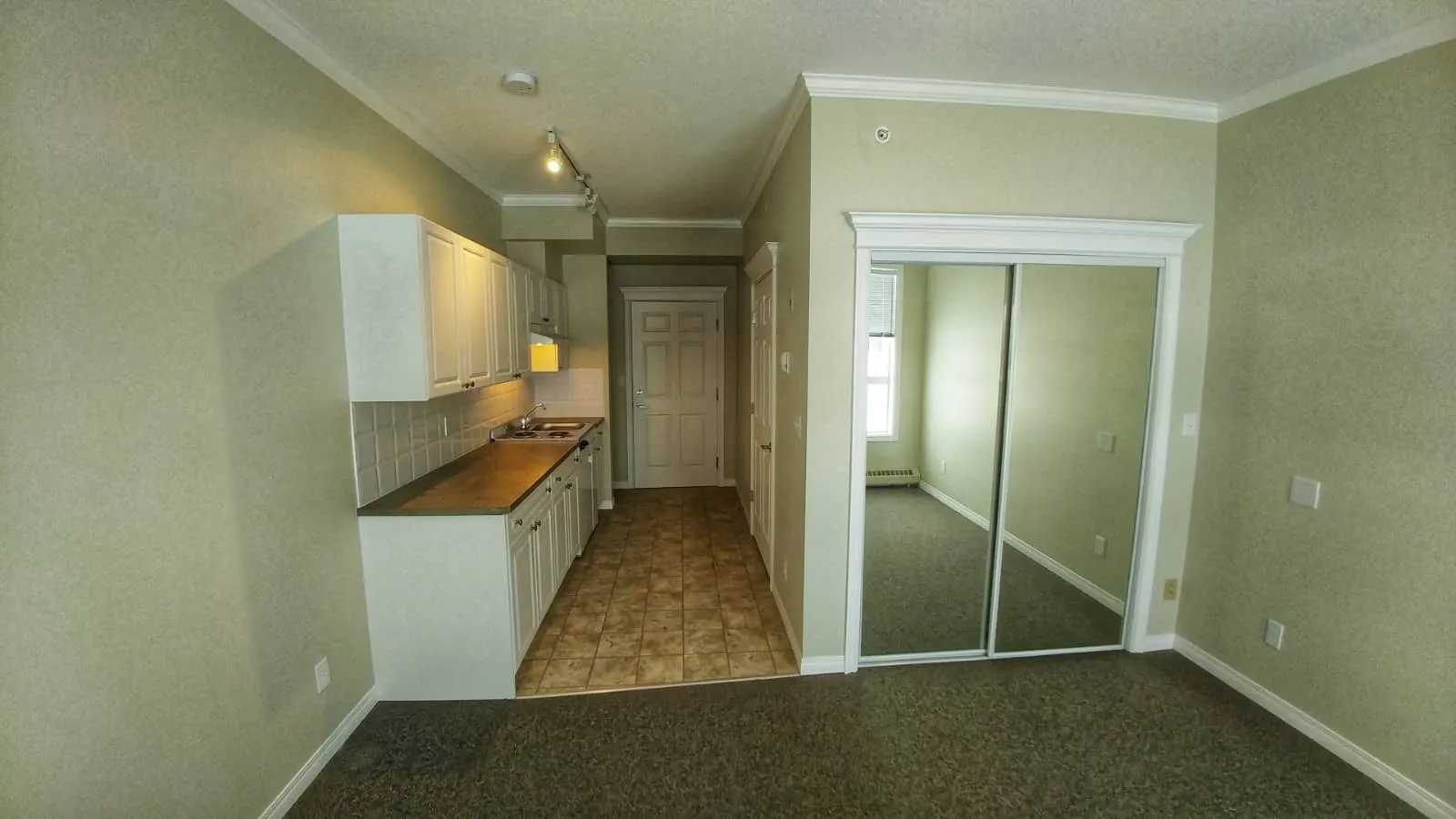 An empty suite ready for a tenant, with a kitchenette and mirrored closet